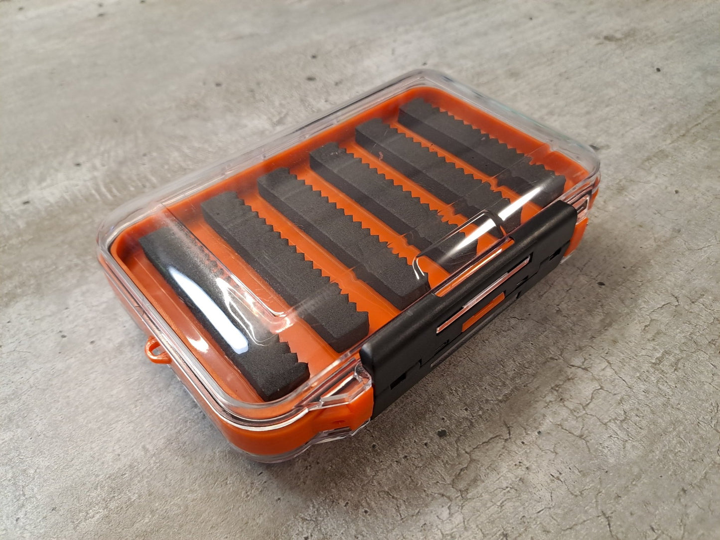 Orange transparente Fliegenbox aus Kunstoff doppelseitig mit schwarzen Schaumstoffeinlagen zur Aufnahme der Fliegen