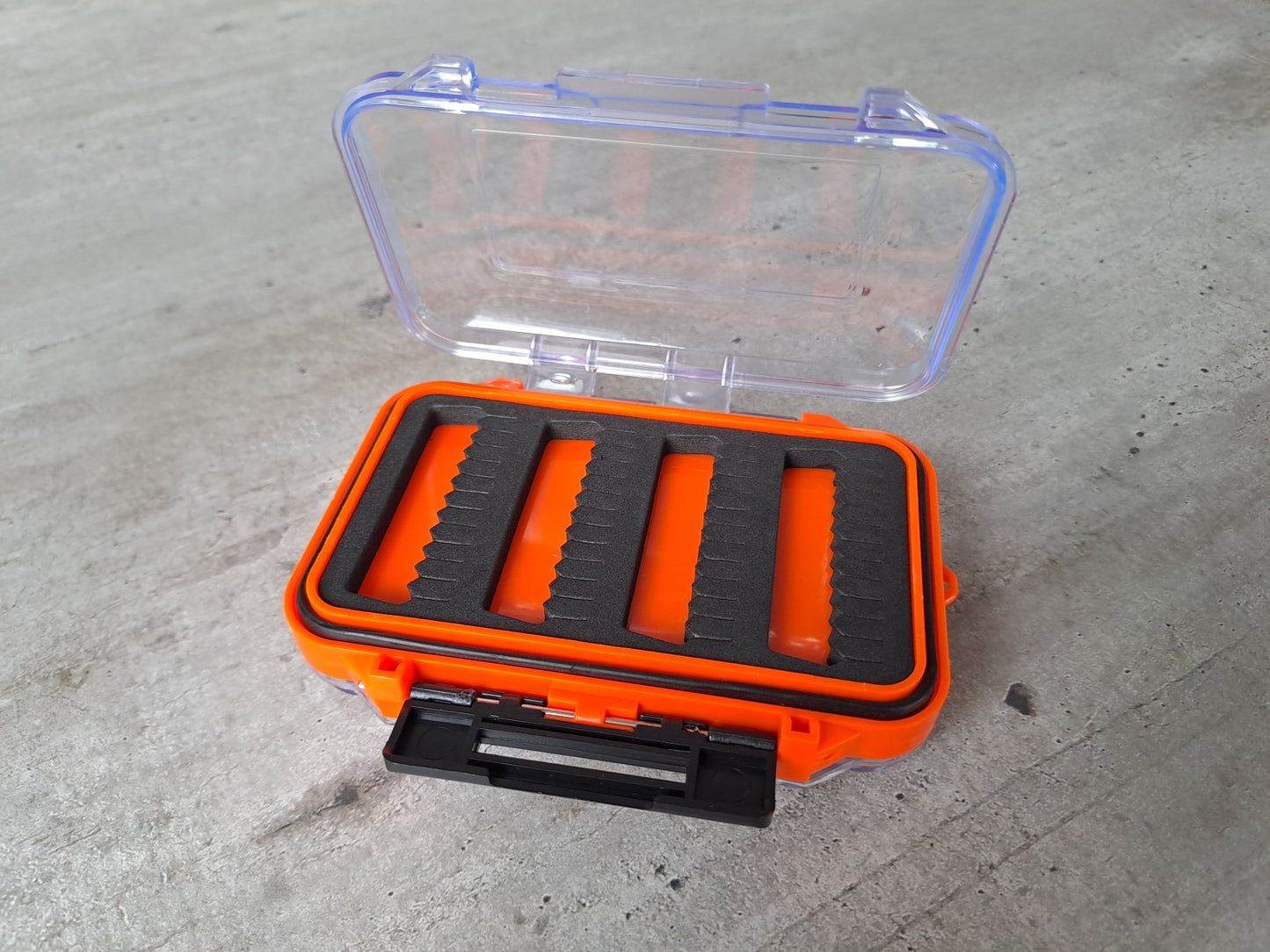 Orange transparente Fliegenbox aus Kunstoff doppelseitig mit schwarzen Schaumstoffeinlagen zur Aufnahme der Fliegen