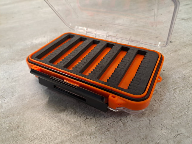 Orange transparente Fliegenbox aus Kunstoff doppelseitig mit schwarzen Schaumstoffeinlagen zur Aufnahme der Fliegen