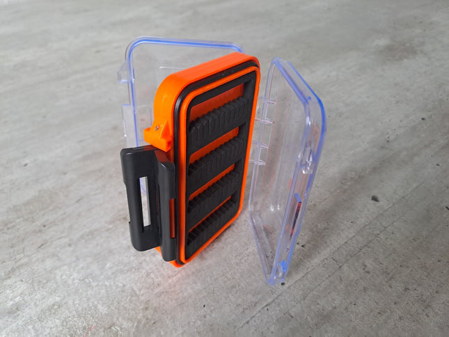 Orange transparente Fliegenbox aus Kunstoff doppelseitig mit schwarzen Schaumstoffeinlagen zur Aufnahme der Fliegen